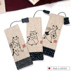 three embroidered bookmarks with cats on them