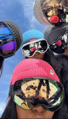 several people wearing ski goggles and hats are looking up at the sky with their reflection in them