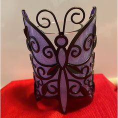 a purple butterfly glass sitting on top of a red cloth