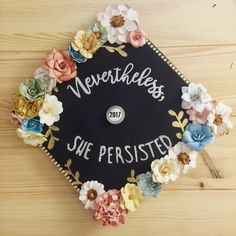 a black graduation cap decorated with flowers and the words merrhees she perished