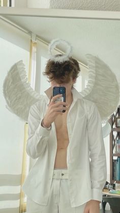 a man taking a selfie in front of a mirror with angel wings on his head