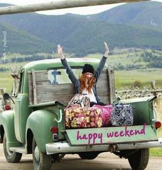 a woman sitting in the back of an old green truck with her arms up and smiling