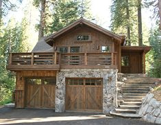 a large wooden house in the woods with stairs leading up to it's entrance