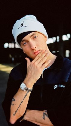 a man with tattoos and a white hat is posing for a photo in the dark