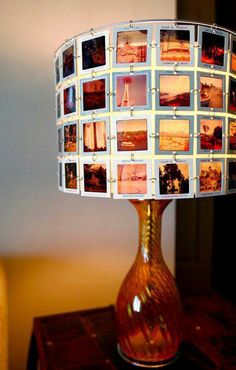 a lamp that has pictures on it sitting on a table in front of a mirror