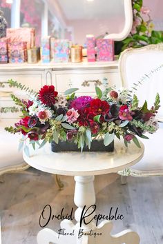 a white table with flowers on it and a mirror in the back ground behind it