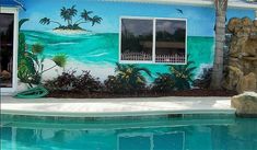 a painting on the side of a house next to a swimming pool with palm trees