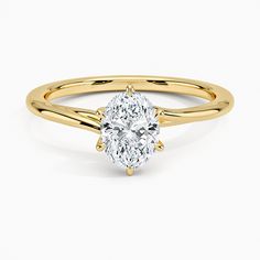 a yellow gold engagement ring with a pear shaped diamond in the center, on a white background