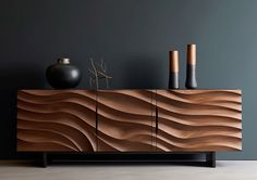 a wooden sideboard with two vases on top and one black vase next to it