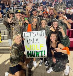 a group of people posing for a photo with a sign that says let's go on a wolf hunt