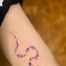 a woman's arm with a tattoo on it that has flowers in the shape of a curved curve