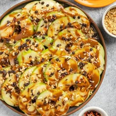 a bowl filled with sliced cucumbers covered in caramel sauce and topped with nuts