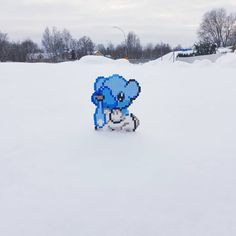 a blue pixellated animal sitting in the snow