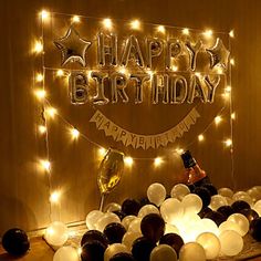 a happy birthday sign surrounded by balloons and lights