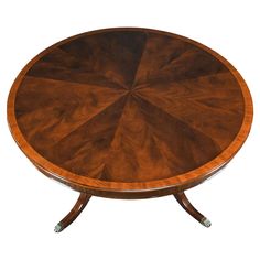 a round wooden table with four legs and a center piece on one end, in the shape of a sunburst