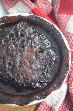 a chocolate cake sitting on top of a wooden table next to a red and white towel