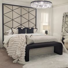 a bedroom with a large bed, mirror and chandelier on the wall above it