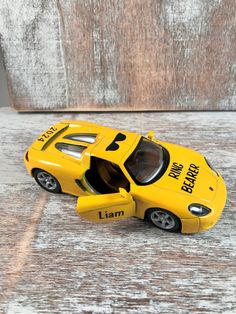 a yellow toy car sitting on top of a wooden table