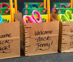 small brown bags with welcome back signs and school supplies in them are lined up on a table