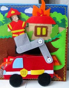 a red fire truck with a boy in the back and a house on top that is made out of felt