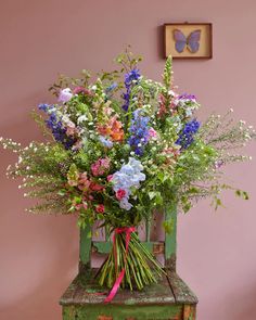 a bouquet of flowers sitting on top of a green chair next to a pink wall