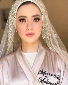 a woman wearing a white veil and headpiece with pearls on the top of her head