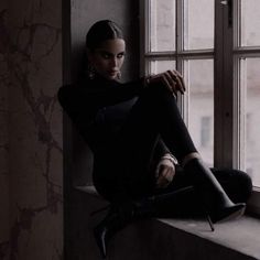 a woman sitting on a window sill looking out the window