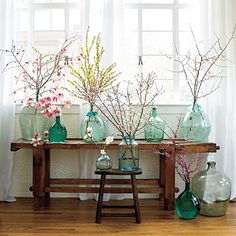 there are many vases with flowers in them on the table next to the window