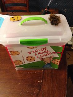 a plastic box with a cookie design on it and a pine cone sticking out of the lid