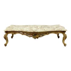 an ornately carved coffee table with marble top and gold leaf accents on the legs