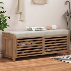 a wooden bench sitting on top of a hard wood floor next to a potted plant