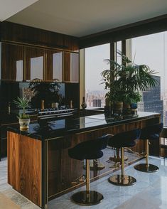 a kitchen with two bar stools next to an island in front of large windows