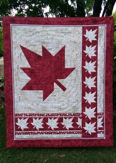 a red and white quilt with a large maple leaf on it's center piece