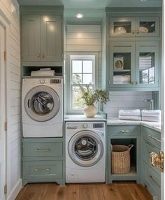 a washer and dryer in a laundry room with green cabinets, wood floors and white walls