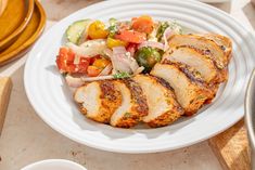 a white plate topped with sliced chicken and veggies