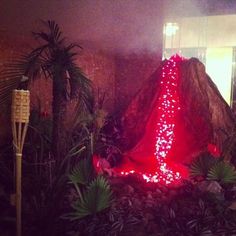 a large rock covered in red lights surrounded by plants