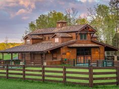 a large wooden house sitting on top of a lush green field