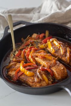 a skillet filled with meat and vegetables on top of a table