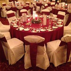 a banquet room set up with white and red linens, silverware and candles