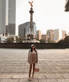 a woman standing in front of a statue with her hand on her hip and holding a purse