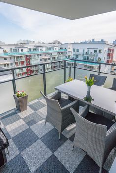 a balcony with chairs, tables and an umbrella on the top floor in front of some balconies