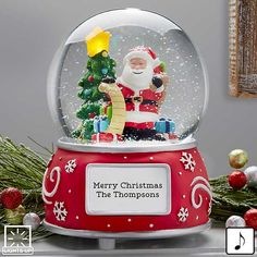 a christmas snow globe with santa claus holding a small tree and presents in the background