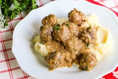 a white plate topped with meatballs and mashed potatoes on top of a red checkered table cloth