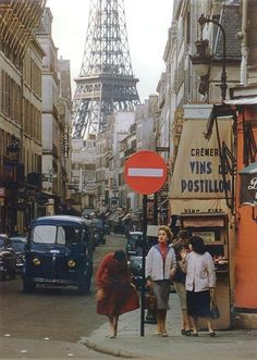 people are walking down the street in front of the eiffel tower