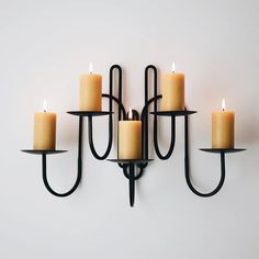 a wall mounted candle holder with six lit candles on it's sides and two in the middle