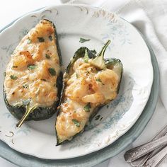 two stuffed green peppers on a plate with silverware and napkins next to them