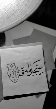 a piece of paper with arabic writing on it next to a lamp and some other items