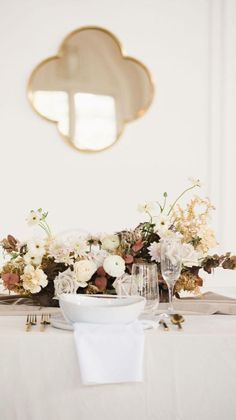 the table is set with white flowers and silverware