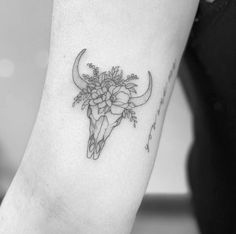 a black and white photo of a cow skull with flowers on it's head