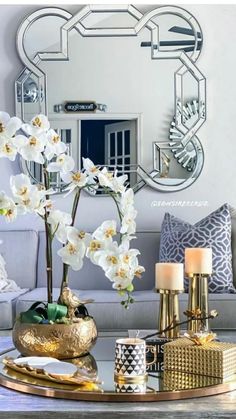 a living room filled with furniture and flowers on top of a table in front of a mirror